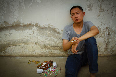 Mature man sitting by narcotics against wall