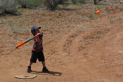 Full length of boy playing baseball on field