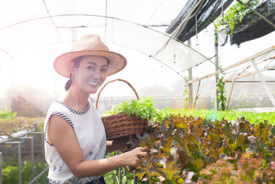 Young woman wearing hat while standing by plants