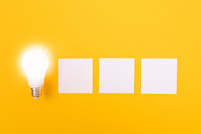 Close-up of illuminated light bulb against yellow background