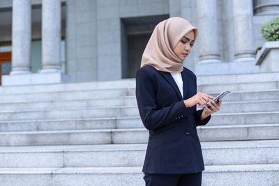 Full length of a woman using mobile phone in city