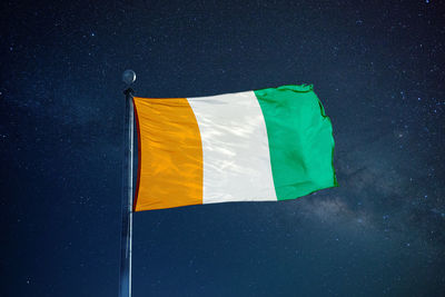 Low angle view of ivorian flag against star field sky