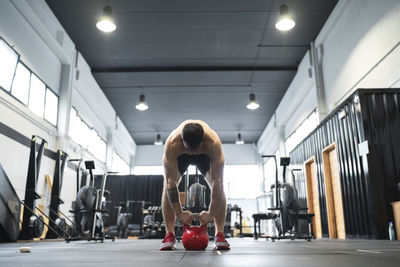 Male athlete holding kettlebell while standing in gym