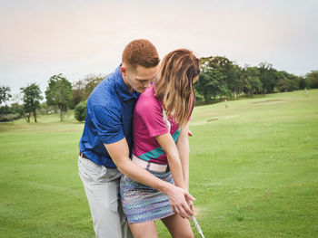 Young woman playing golf with man