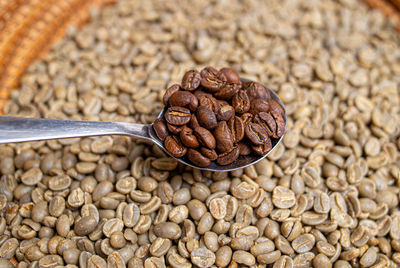 Close-up of roasted coffee beans above raw beans