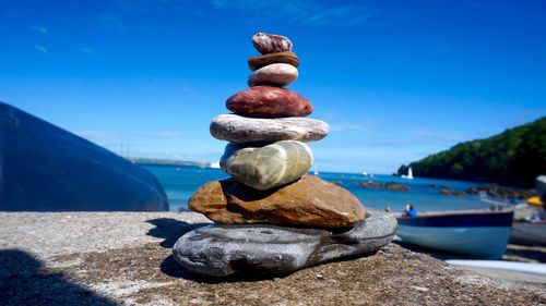 Stack of pebbles in sea against blue sky