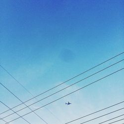 Low angle view of power lines against clear blue sky