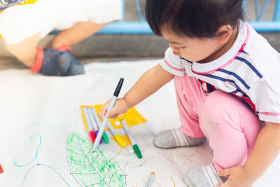 High angle view of girl holding paper on table