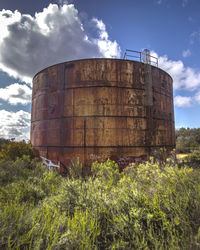 Storage tank against cloudy sky