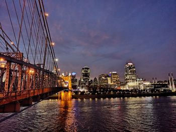 Illuminated bridge over river against sky at night