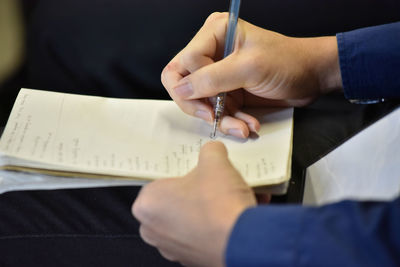 Midsection of man reading book on paper