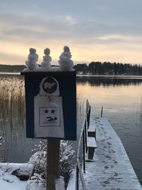 Information sign on wooden post in lake during winter