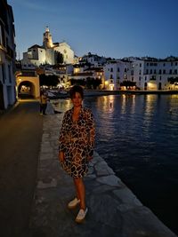 Woman standing by buildings in city against sky