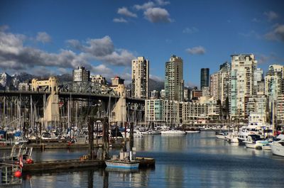 Sailboats moored in harbor against buildings in city