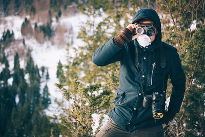 Full length of woman photographing in forest