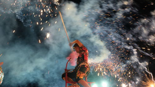 Low angle view of woman with fire crackers at night