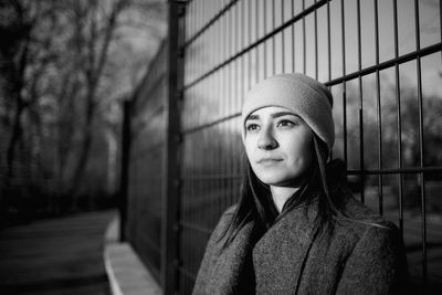 Woman looking away against fence