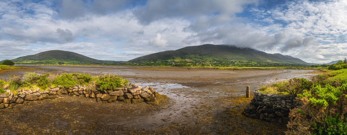 Large panorama with dry lagoon after ebb tide with stone pier and mountain range, ireland