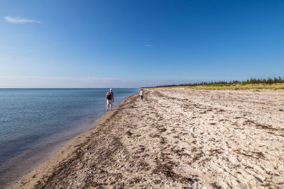 People walking on beach against sky