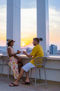 Full length of woman sitting on chair at beach