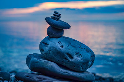 Close-up of stone stack on rock at beach against sky