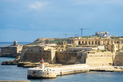 Buildings by sea against sky