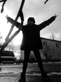 Full length of young woman standing against sky