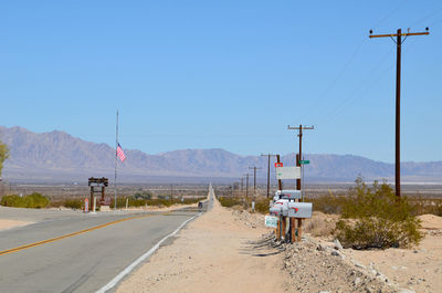 Road leading towards mountains against clear sky