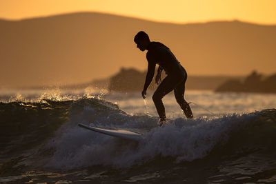 Full length of man on sea against sky during sunset