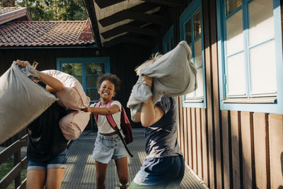 Happy kids pillow fighting while standing in corridor near cabins