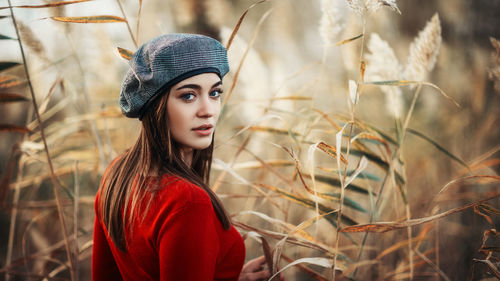 Portrait of young woman standing against plants