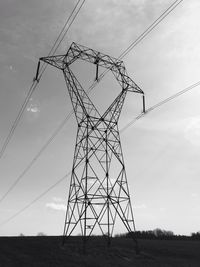 Low angle view of electricity pylon on field