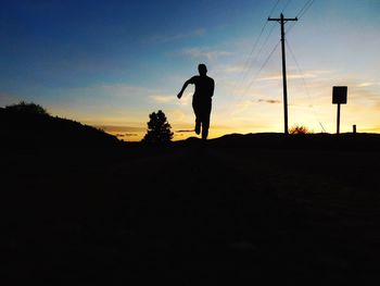 Silhouette man playing soccer on field against sky during sunset