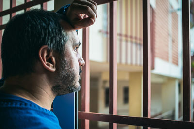 Portrait of young man looking through window