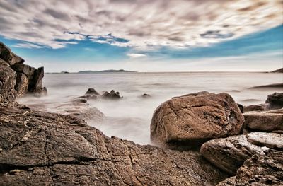 Rocks on sea shore against sky