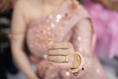 Midsection of woman holding pearl jewelry