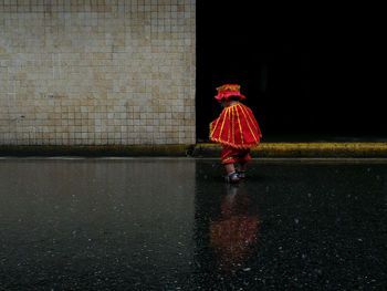 Rear view of woman walking on wet street during monsoon