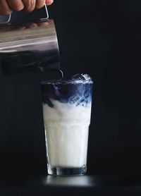 Close-up of hand pouring drink in glass