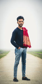 Portrait of young man standing on land against clear sky