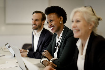 Smiling female professional planning with colleagues in meeting at board room