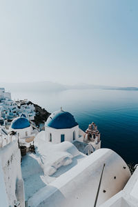 Houses by sea against clear sky