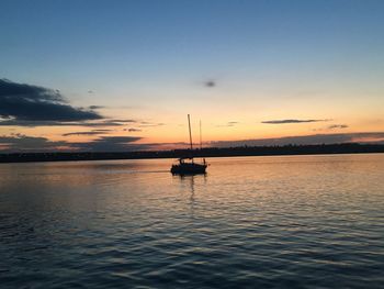 Silhouette sailboats in sea against sky during sunset