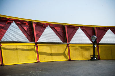 Yellow metallic structure against building against sky