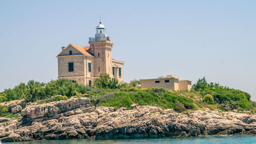 Lighthouse on hill against sky