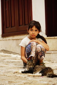 Portrait of cute girl sitting on wall