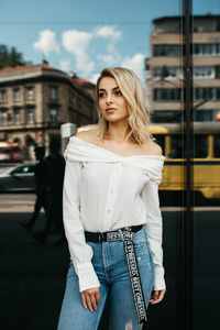 Fashionable woman standing against window in city