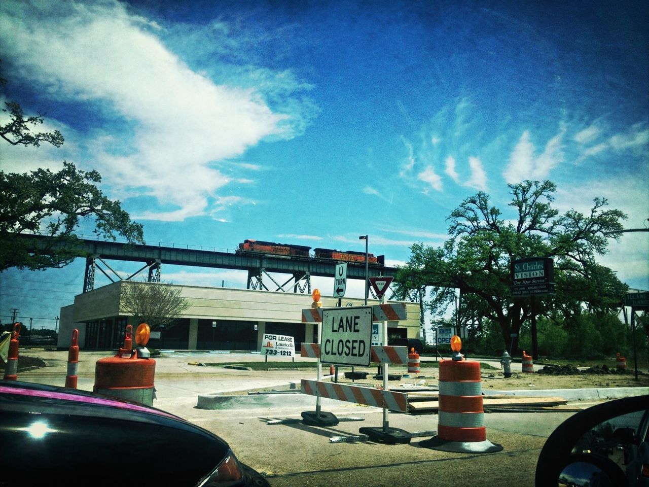 transportation, land vehicle, sky, mode of transport, car, built structure, architecture, cloud - sky, parking, tree, stationary, parked, outdoors, sunlight, day, street, cloud, no people, building exterior, road