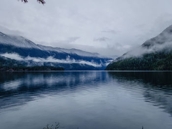 Scenic view of lake and mountains in foggy weather