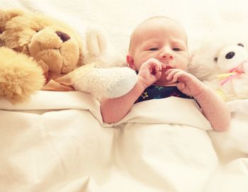 Portrait of cute baby girl lying on bed