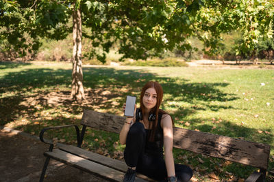 Young woman sitting on bench in park
